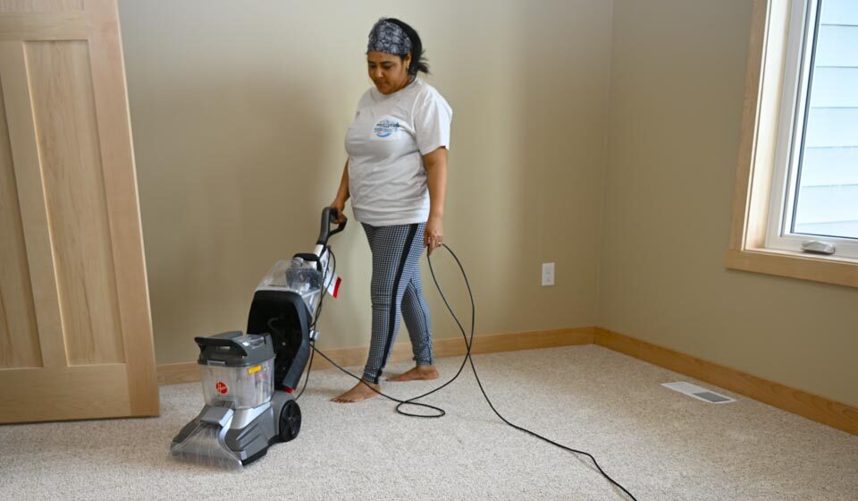 Woman from cleaning service vacuuming carpet